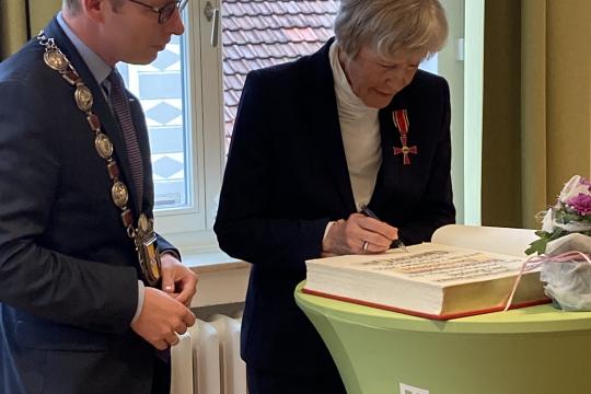 Im Beisein von Bürgermeister Christian Schweitzer (l.) trägt sich Gudrun Gille ins Goldene Buch der Stadt Hemer ein. 